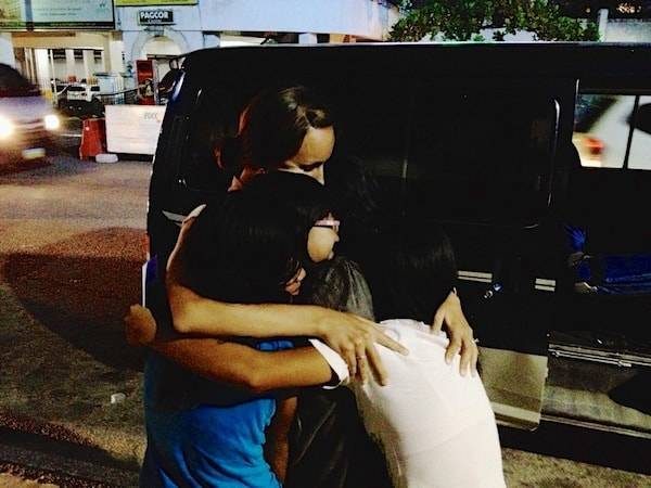 Woman hugging children.