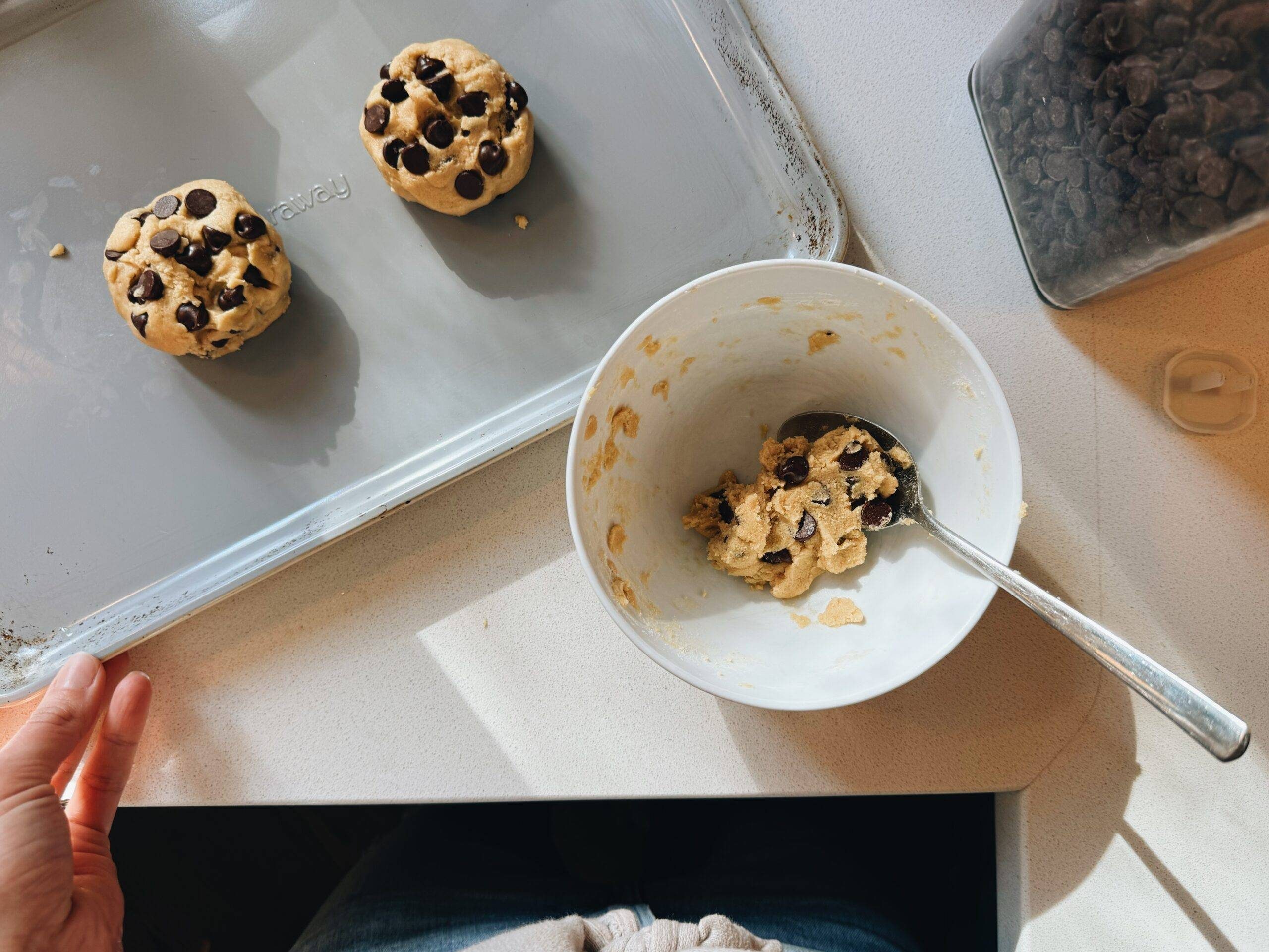 Two cookie dough balls on a sheet pan.