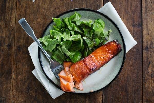 Caramelized salmon on a plate with greens.