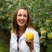 A woman holding up an Opal apple.