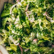 Salad with lettuce, fresh herbs, and pickled onions in a bowl.