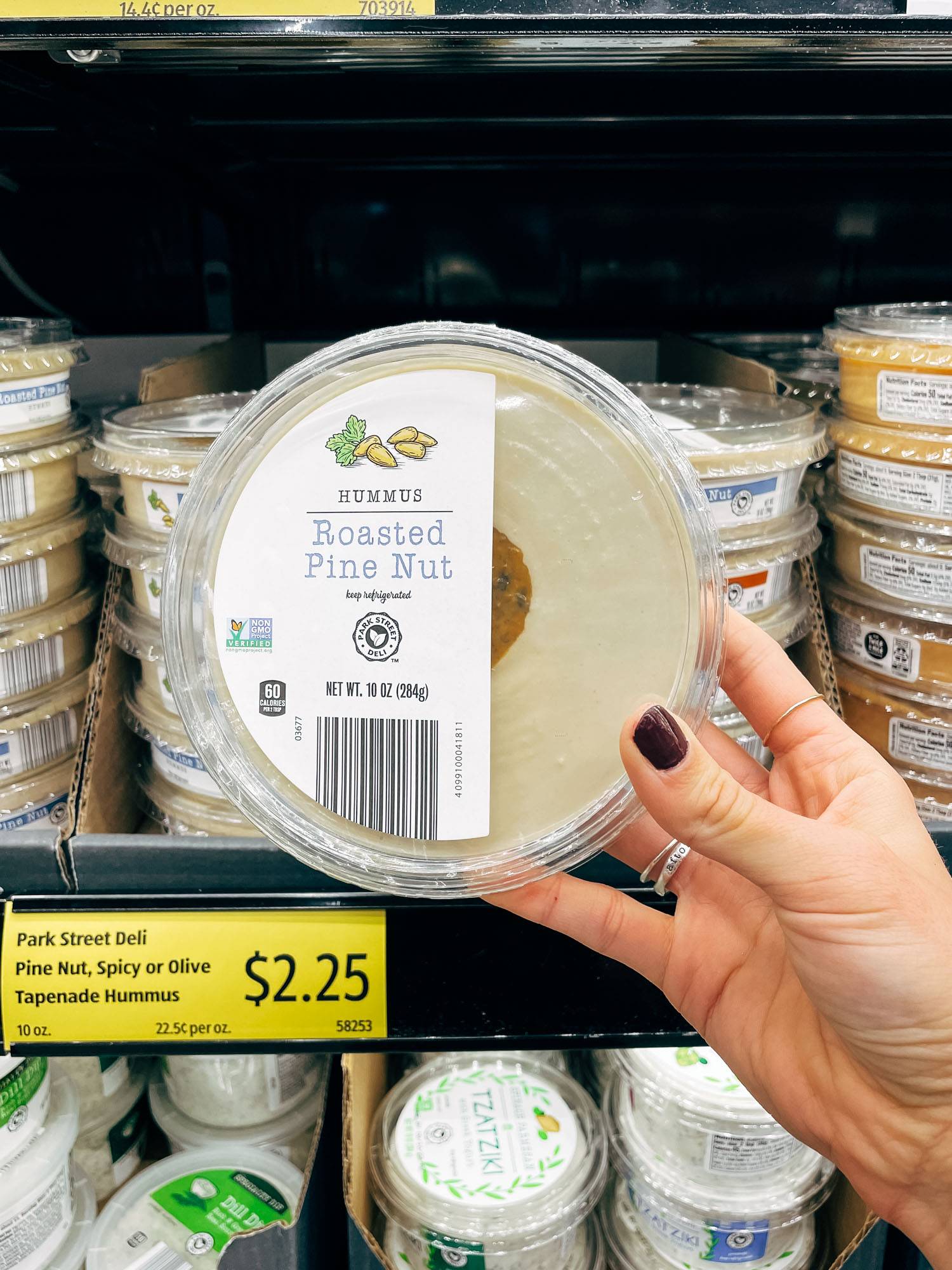 White hand holding a container of hummus