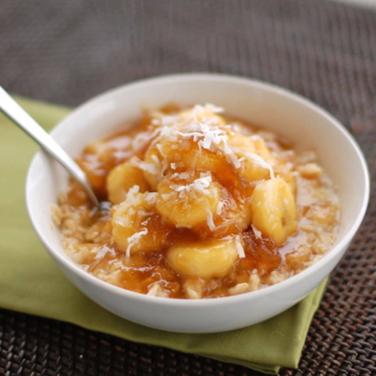 Caramelized banana and fig oatmeal in a bowl with a spoon on a green napkin.