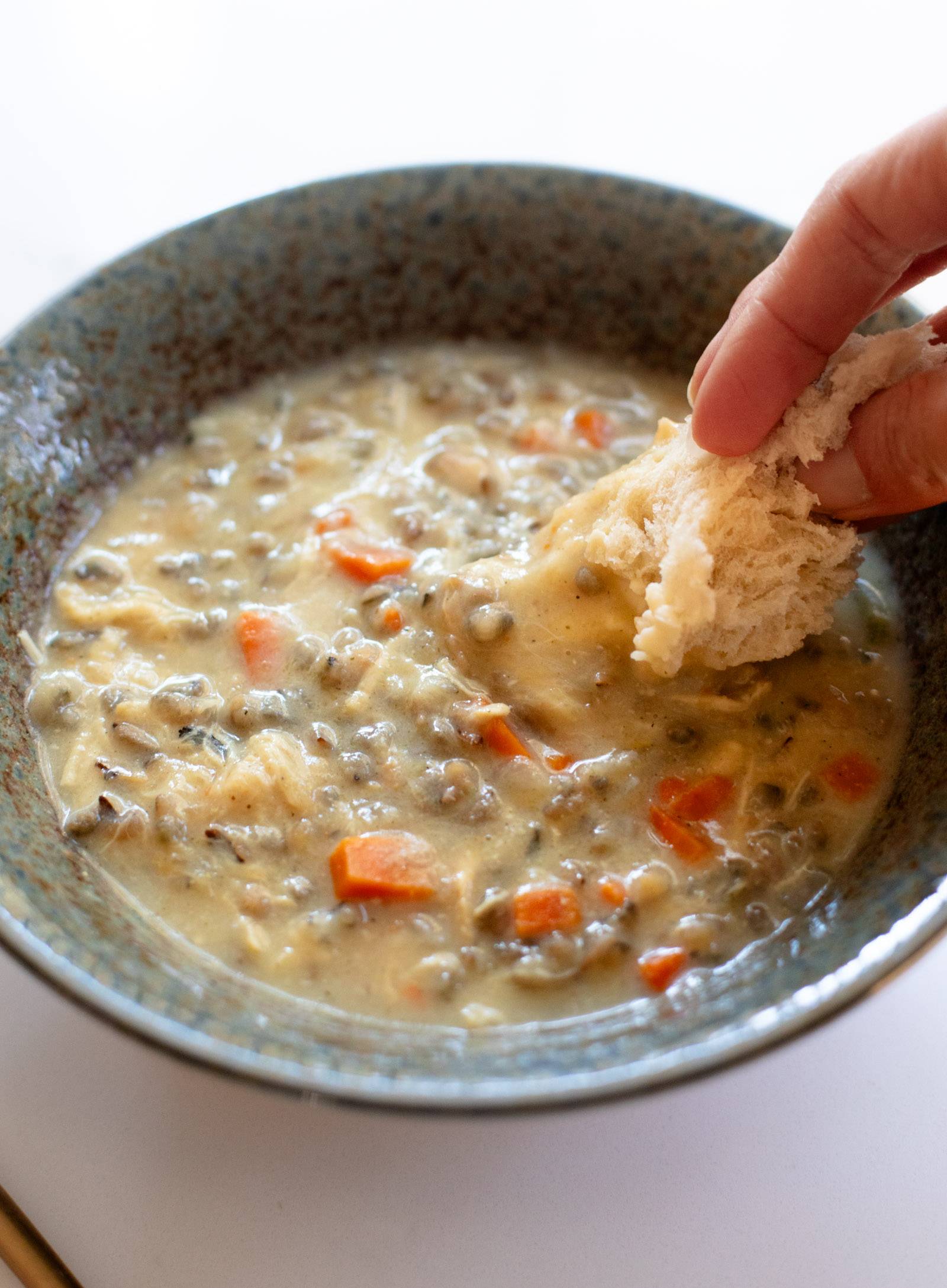 Crockpot Chicken Wild Rice Soup in a bowl with bread dipping