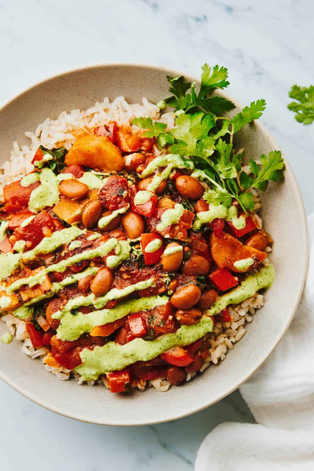 Plantain and Pinto Stew in a bowl with rice and aji verde.
